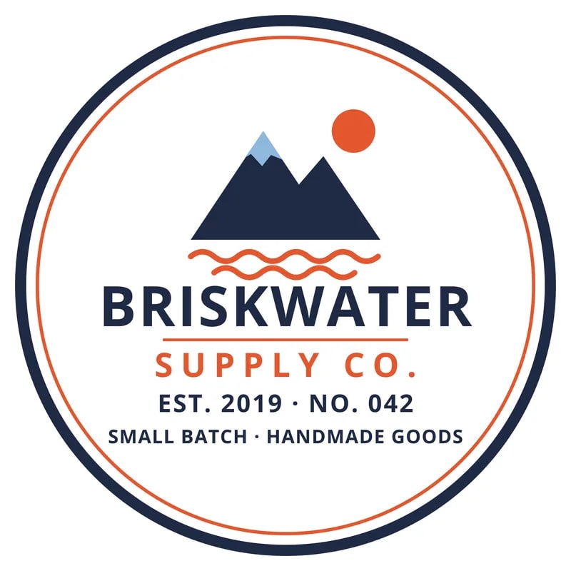Round Briskwater Supply Co. badge logo with a navy ring, mountains, an orange sun and four lines of small text