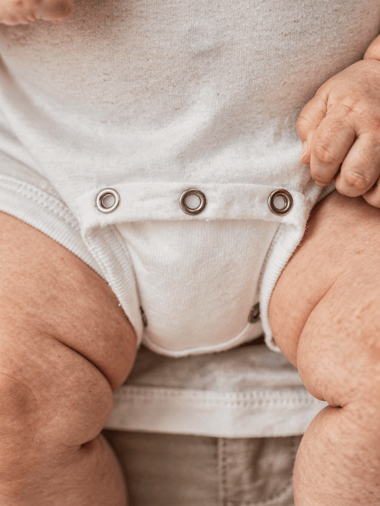 White Polyester Baby Onesie Mockup on Model — Snap Closure Detail